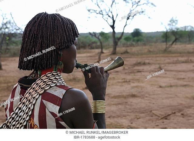 Young woman from the Hamar tribe blowing a horn in order to gain attention during the bull-leaping ceremony, an initiation rite, southern Omo Valley, Ethiopia