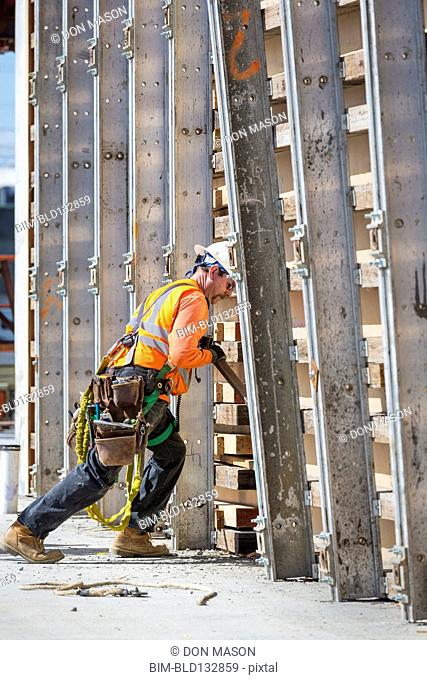 Caucasian worker pushing wall form at construction site