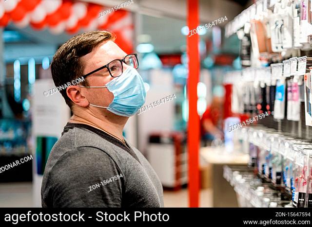 Caucasian man shopping for clothes with medical mask. New normal concept. . High quality photo