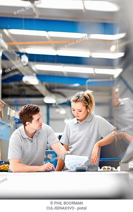 Manager advising female worker on production line in factory