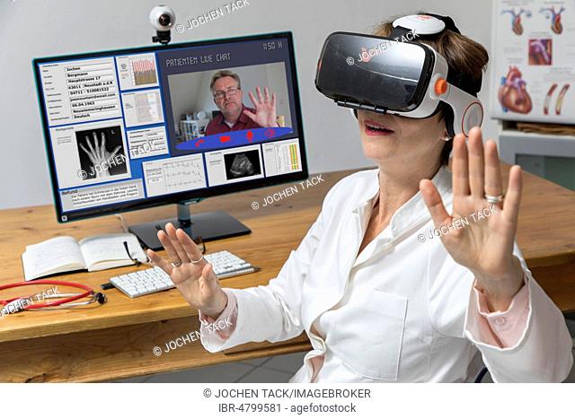 Symbol photo for telemedicine, doctor in a practice, with VR glasses, Virtual Reality, 3-D presentation of an MRT result