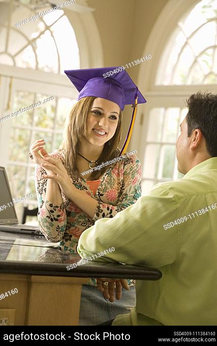 Father admiring daughter's graduation cap