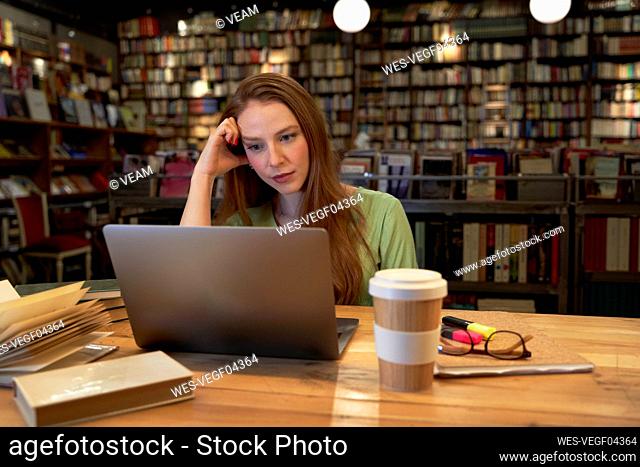 Young woman studying through laptop in library