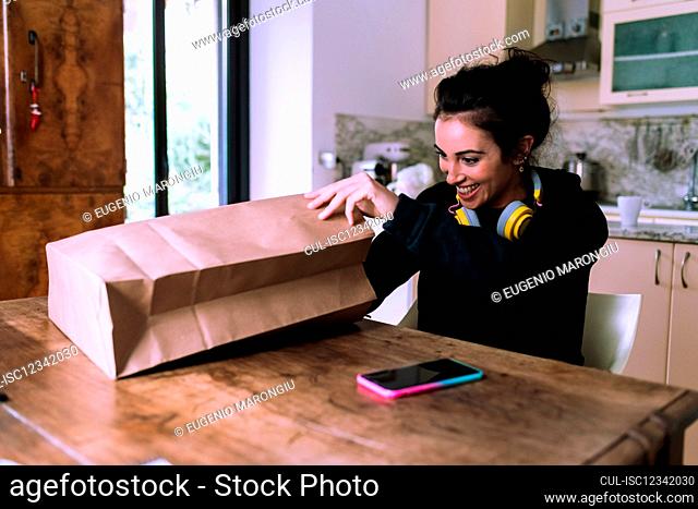 Woman at home, looking inside paper shopping bag