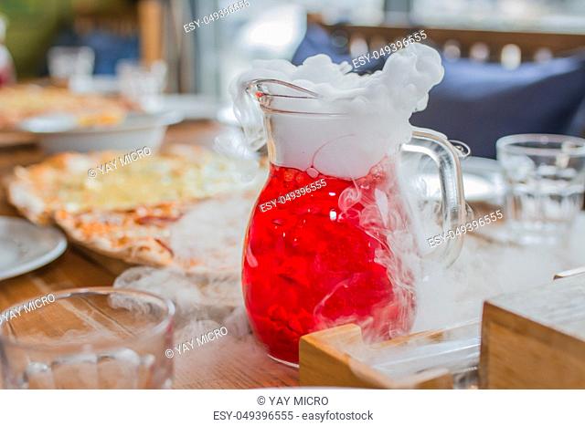 Red cold juice with steam and smoke on birthday party table
