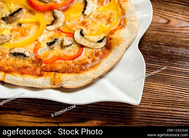 Close up shot of small pizza with mushrooms and peppers