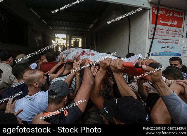 05 August 2022, Palestinian Territories, Gaza City: Palestinians carry the body of a person who was killed in an Israeli airstrike