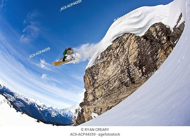 A snowboarder airs off a snow pillow while on a cat ski trip. Monashee Mountains, Vernon, Britsh Columbia, Canada