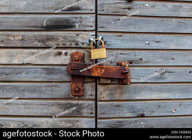 Close up detailed view of an old wooden door with an iron padlock