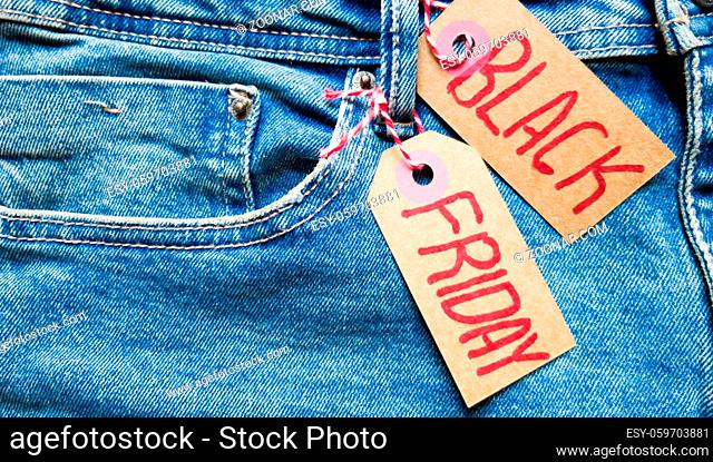 Stylish jeans with a black friday flag. Black friday and cyber monday sale discount concept tag with blue jeans. Black friday written on grunge jeans texture