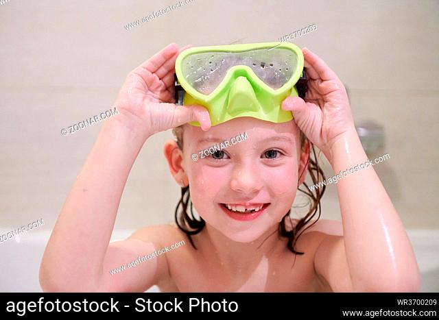 little girl with snorkel goggles in the tub while taking a bath in the bathtub, kids hygiene concept and summer vacation in corona virus stay at home