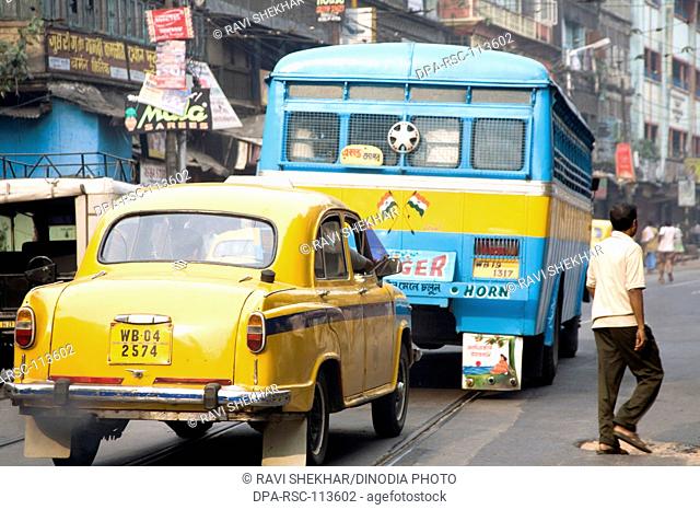 Street scene ; yellow color taxi behind blue bus ; Calcutta now Kolkata ; West Bengal ; India