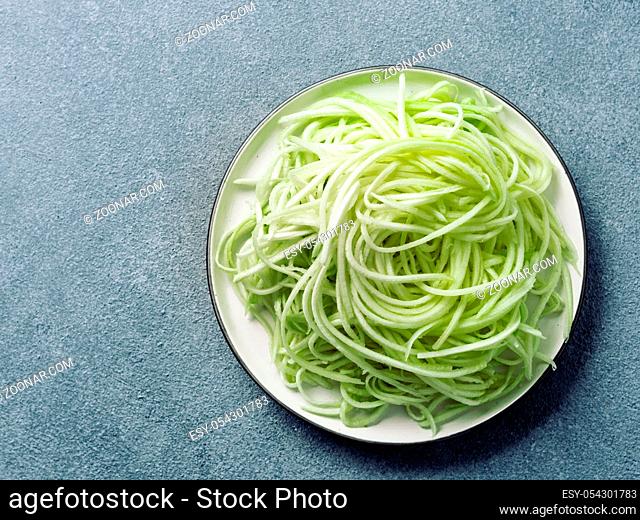 Zucchini noodles on plate.Vegetable noodles -green zoodles or courgette spaghetti on plate over gray stone background.Clean eating, raw vegetarian food concept