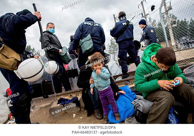 Refugees wait next to Greek police officers by the border fence in the refugee camp at the Greek-Macedonian border near Idomeni, Greece, 07 March 2016