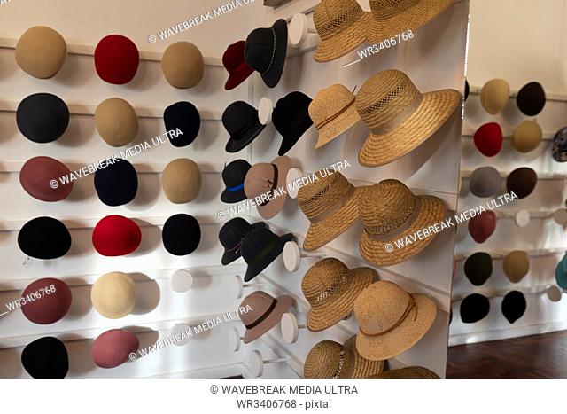 Various styles of hats for men and women displayed in rows on the white walls of the showroom at a hat makers