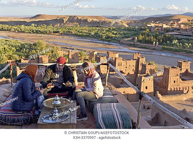 people sitting on the terrace of a cafe overlooking the Ksar of Ait-Ben-Haddou, Ounila River valley, Ouarzazate Province, region of Draa-Tafilalet, Morocco