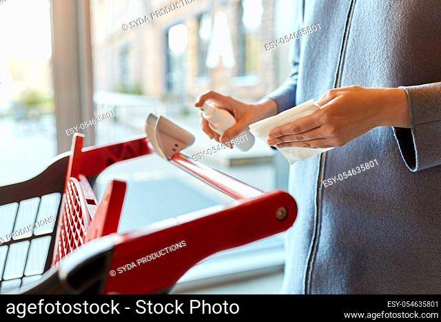 woman cleaning shopping cart handle with sanitizer