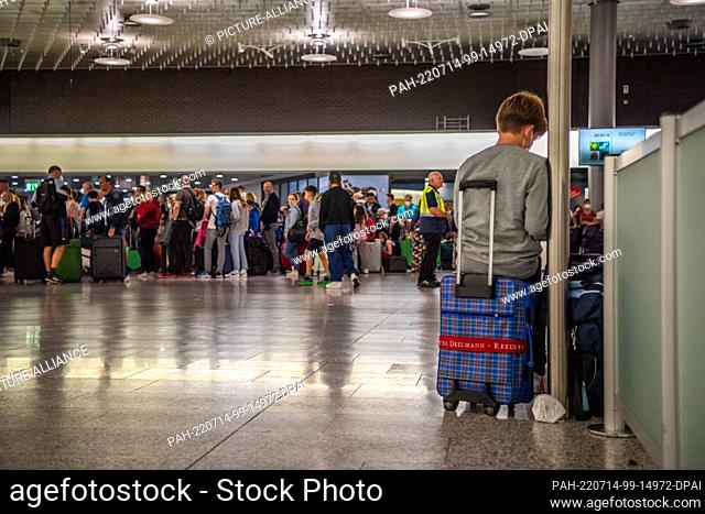 14 July 2022, Lower Saxony, Hanover: A child waits, leaning against a pillar in the waiting area, for his check-in counter to open at Hannover Airport