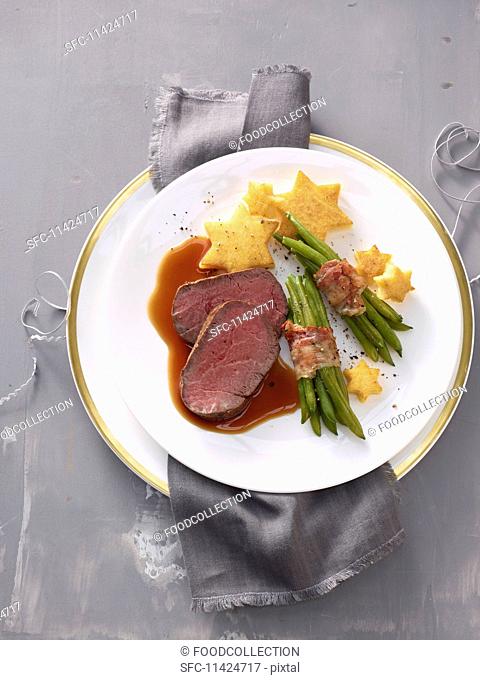 Beef fillet with polenta stars and beans wrapped in bacon