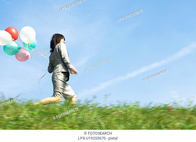 Businesswoman holding a bunch of balloons