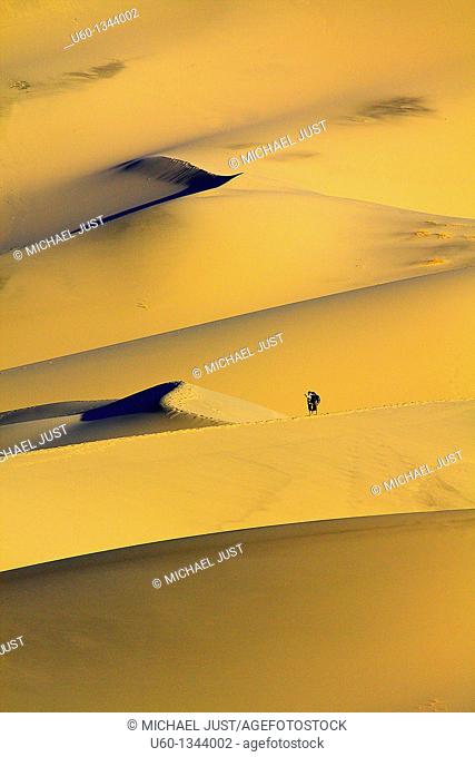 Hikers make their way up Eureka Dunes at Death Valley National Park