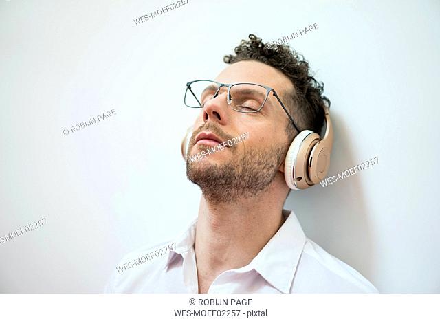 Businessman with closed eyes listening to music with headphones