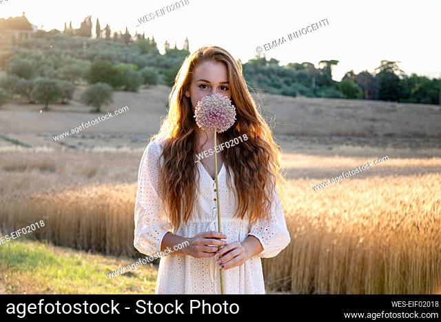 Young woman holding garlic flower on agricultural field