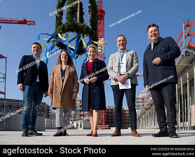 25 March 2022, Berlin: A topping-out wreath hangs behind Governing Mayor Franziska Giffey (M, SPD) and Building Senator Andreas Geisel (r) and representatives...