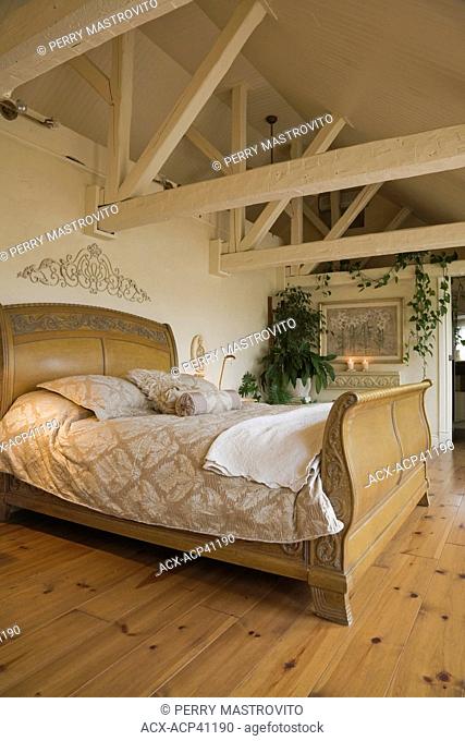 Wooden sleigh bed and furnishings in the master bedroom in the attic of an old circa 1840 cottage style residential home, Quebec, Canada