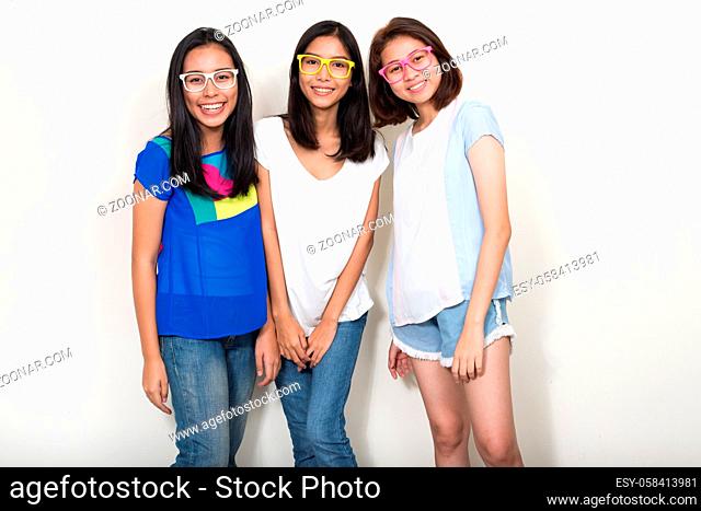 Studio shot of three young beautiful Asian teenage girls as friends together against white background
