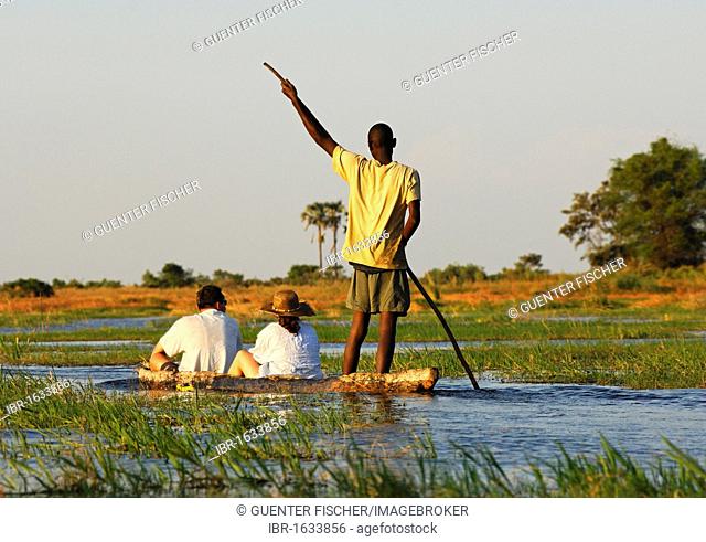 Punter with tourists in the traditional Mokoro dugout canoes on excursion in the Okavango Delta, Botswana, Africa