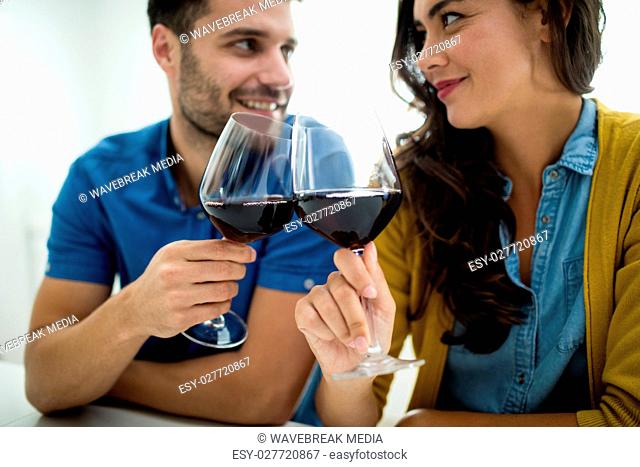 Couple toasting glasses of red wine in the kitchen