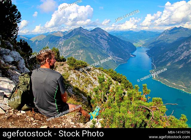 middle-aged man enjoys the view from bärenkopf (1991m), achensee, on the left seebergspitze and seekarspitze, on the right rofan mountains, tyrol, austria