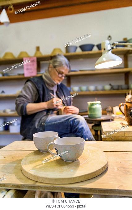 Potter in workshop with cups in foreground