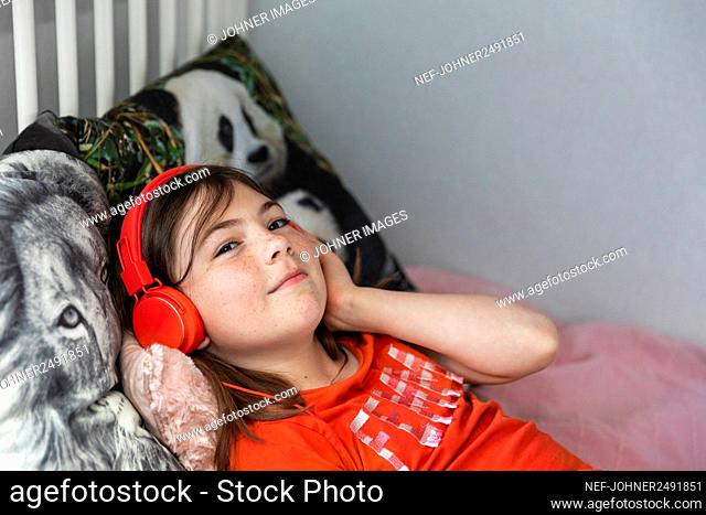 Girl with on bed wearing headphones