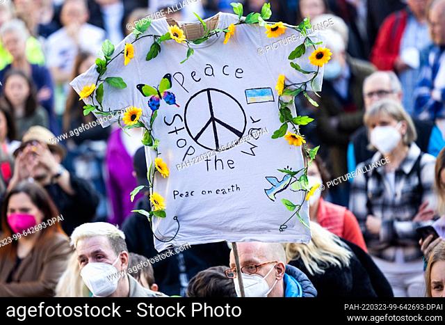 23 March 2022, North Rhine-Westphalia, Cologne: ""Peace stop the war"" is written on a T-shirt decorated with flowers at a peace rally with a benefit concert...