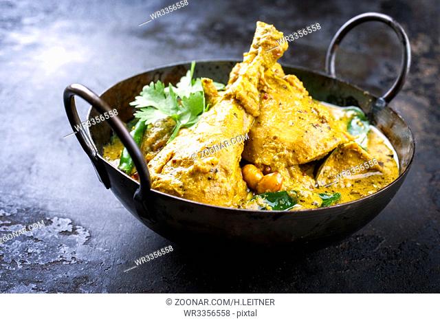 Traditional Indian curry chicken as close-up in a korai