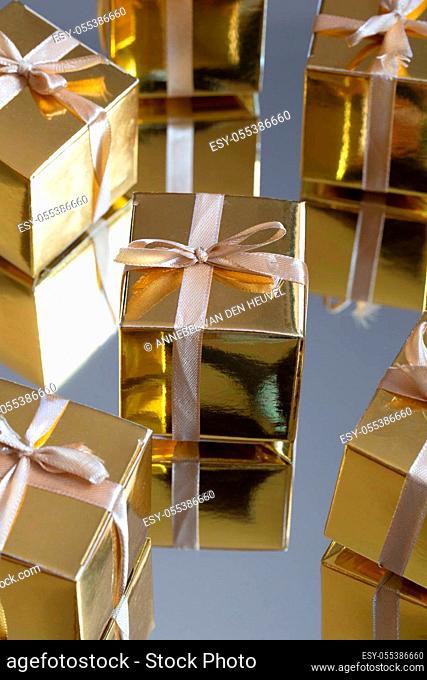 Group of gold sparkling gift boxes on grey background with reflection. A set of gold gift boxes for present, suprise, birthday, Christmas concept beauty