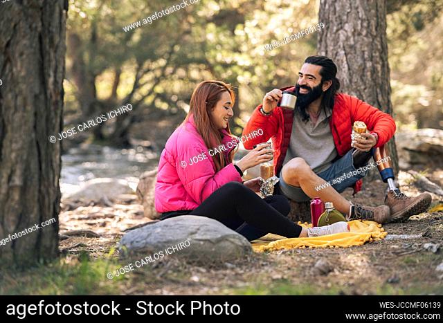Happy couple with food and drink enjoying in forest