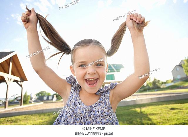 Caucasian girl playing with pigtails outdoors