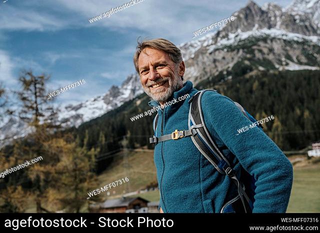 Smiling mature man with backpack standing against sky at Hochkonig, Salzburger Land, Austria