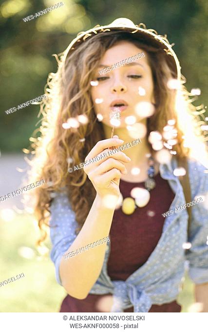 Young woman blowing dandelion