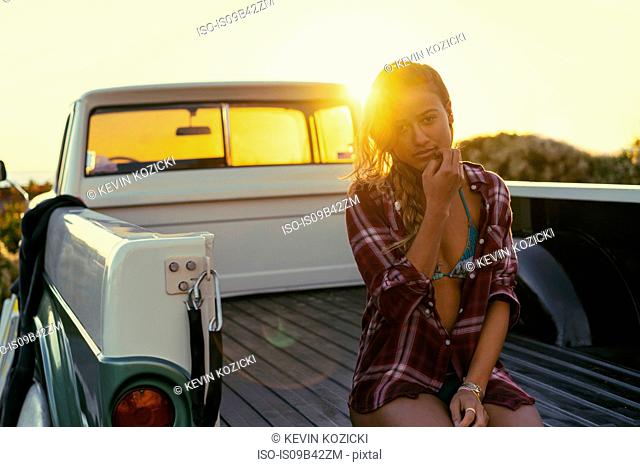 Portrait of young female surfer in back of pickup truck at Newport Beach, California, USA