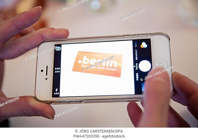 ILLUSTRATION - A woman takes a photo of a sticker with the domain name '.berlin' with her smartphone in Berlin, Germany, 18 March 2014