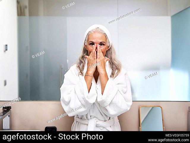 Mature woman massaging nose in bathroom
