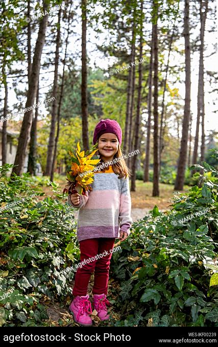 Smiling girl holding bunch of leaves