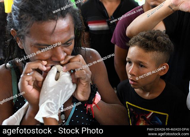 25 April 2023, Mexico, Huixtla: A child watches as Deborah Sofia from Venezuela has her mouth sewn shut in a protest. Migrants did so to protest Mexico's...