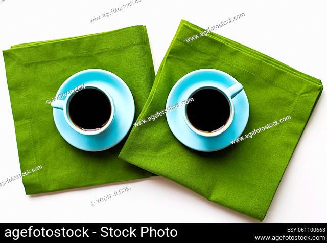 two blue cups of coffee on a table with green cloth