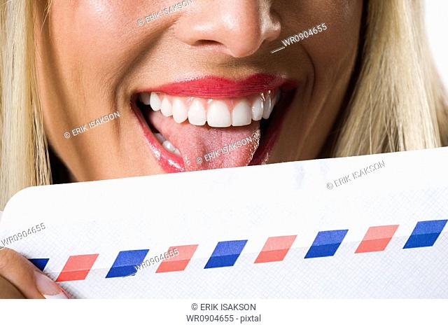 Close-up of a young woman licking an envelope