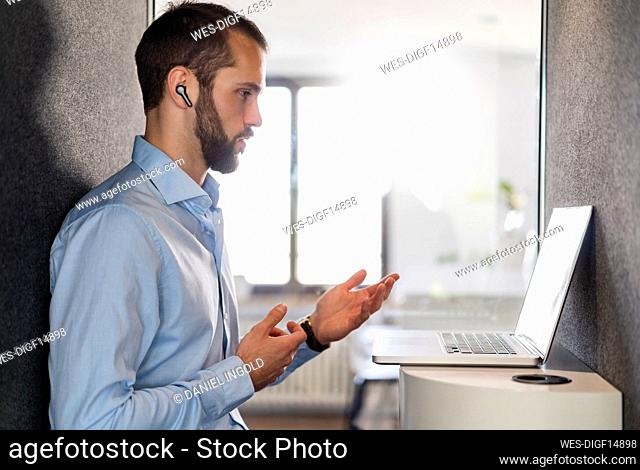 Businessman gesturing while talking on video call over laptop at office